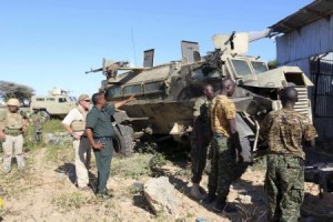 Africa Union (AU) troops stand next to an armoured carrier targeted by suicide car bomb attackers while travelling in a convoy outside the capital Mogadishu