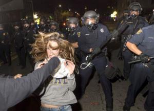 A protester flees as police officers try to disperse a crowd comprised largely of student demonstrators during a protest against police violence in the U.S., in Berkeley, California early