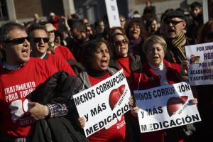 People supporting those affected by hepatitis C shout and hold banners racing 'less corruption and more medication' during a demonstration in Madrid, Spain